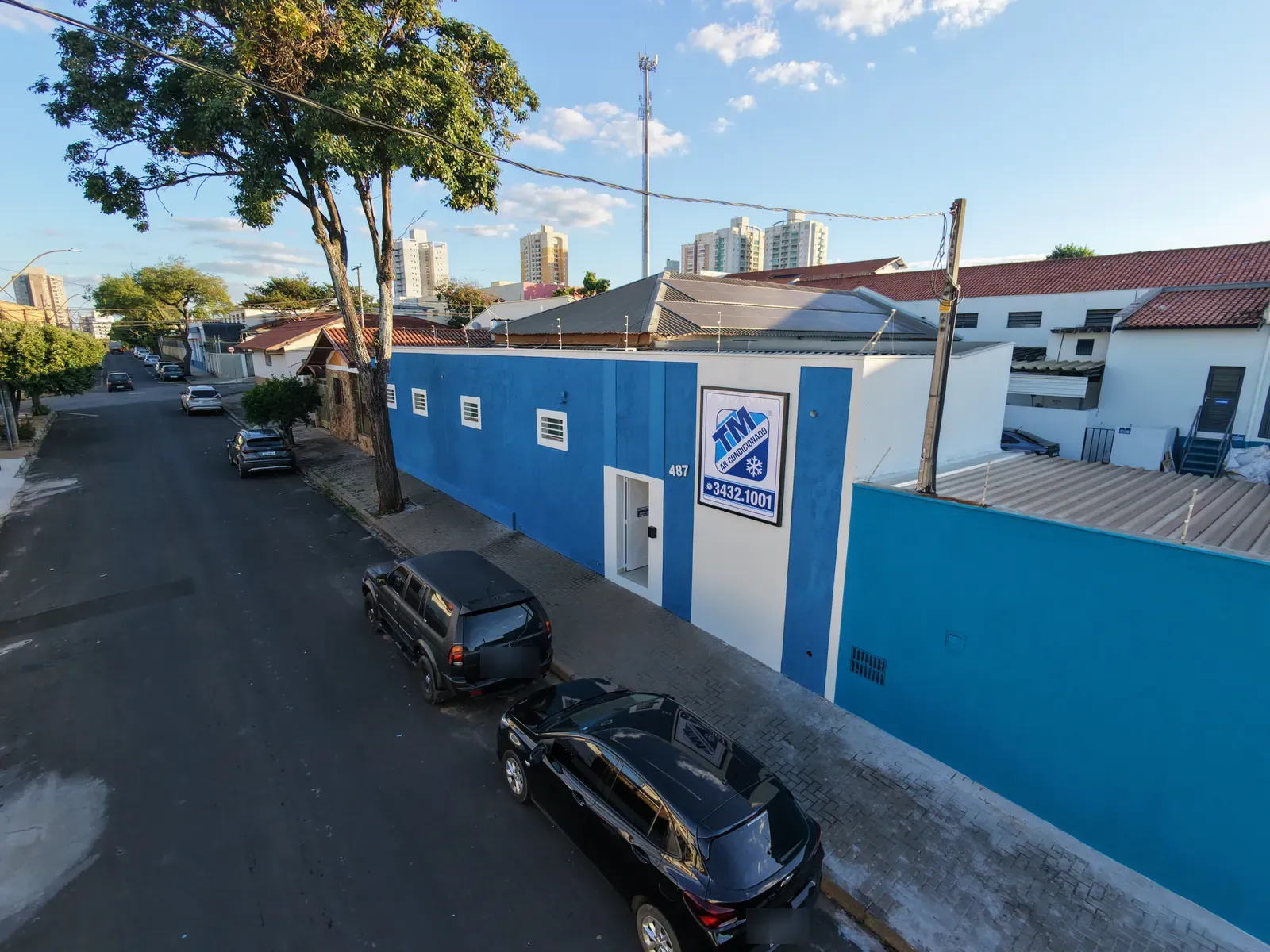 Sede da TM Ar Condicionado ao entardecer, prédio azul com letreiro da marca